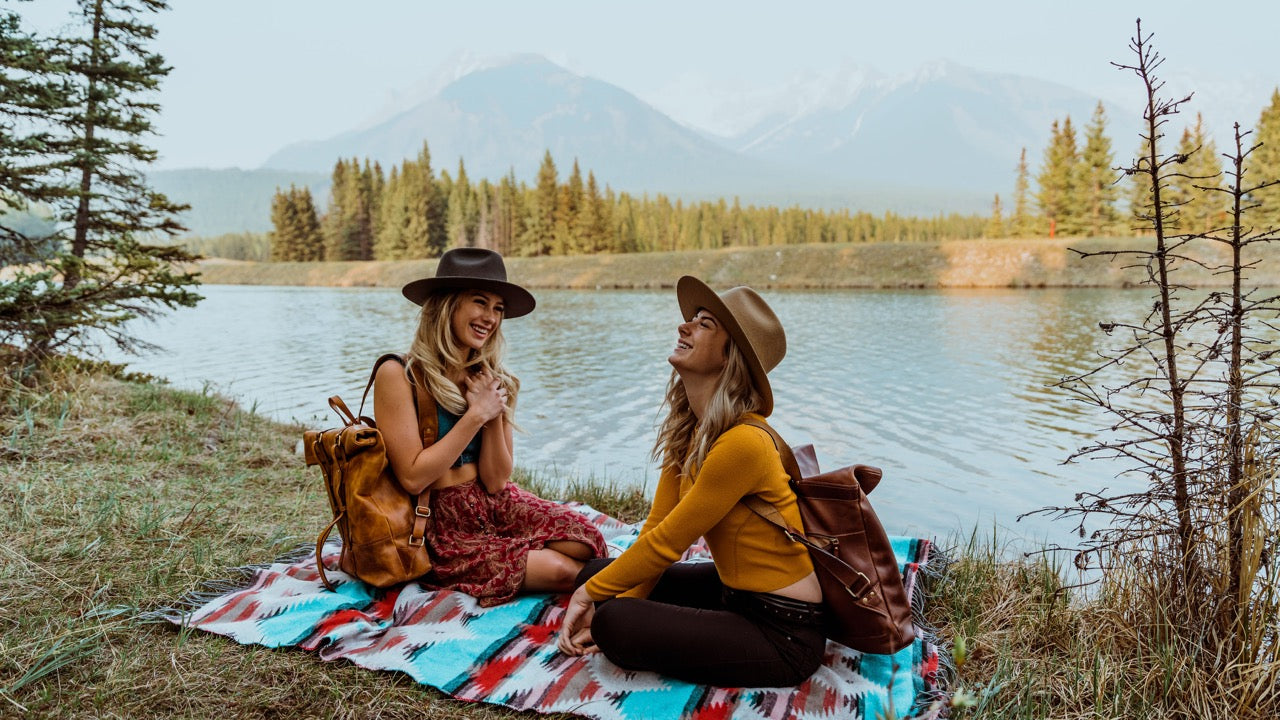 Piknik am See mit Lederrucksaecken und zwei Frauen